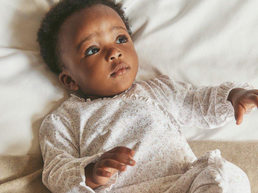 a baby laying on a bed with a blanket on it