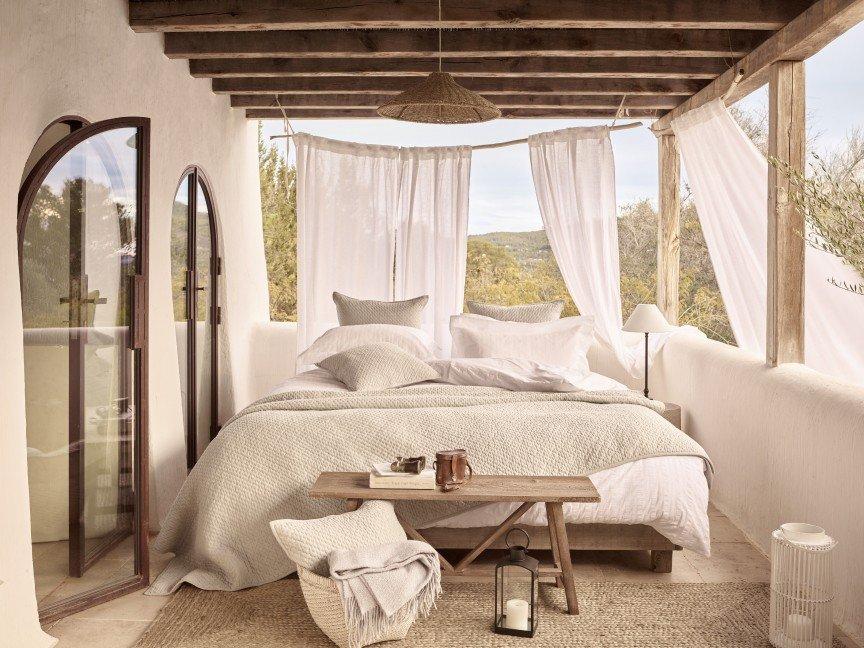 a bedroom with a bed, table, and chairs in a white room