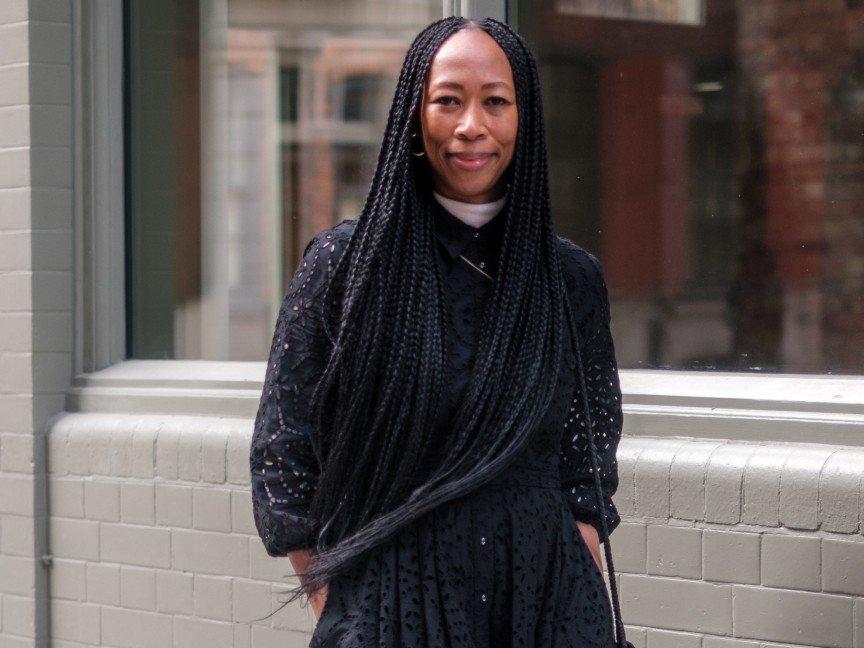 a woman with long braids standing outside on a sidewalk