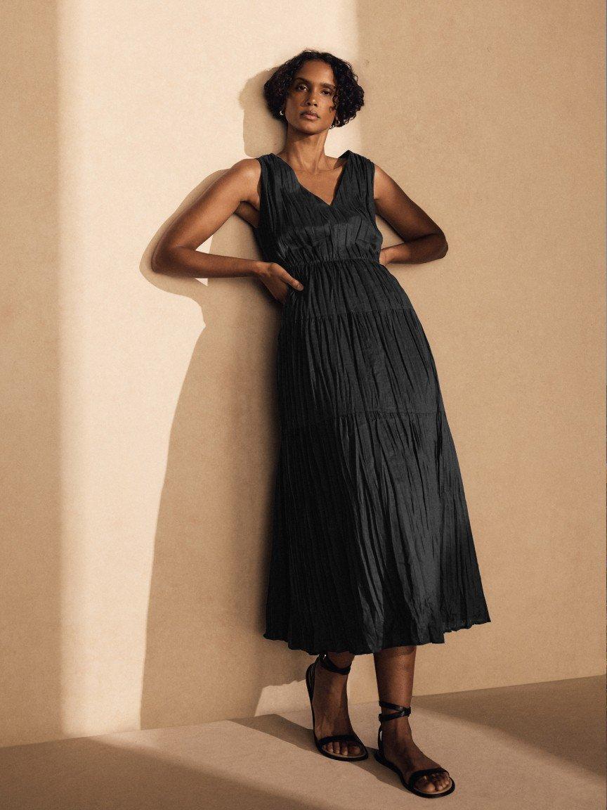 a woman in a black dress leaning against a wall