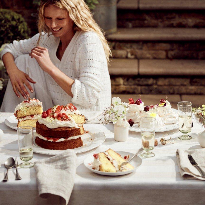 a woman sitting at a table with a plate of cake