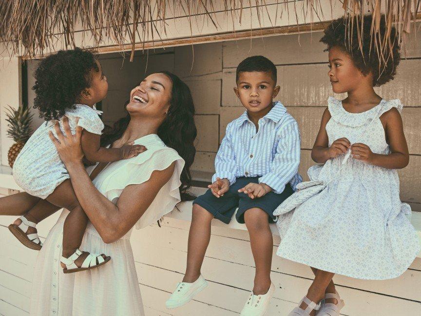 a woman holding two children and one standing next to her