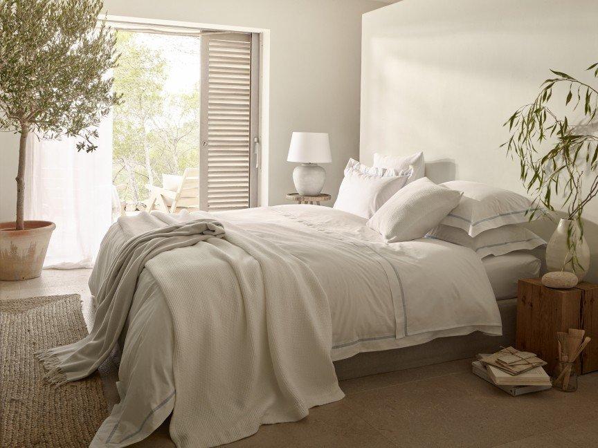 a bedroom with a bed, a table, a potted plant and a window