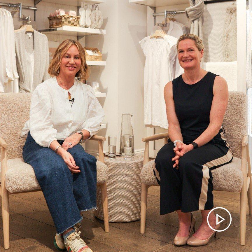 two women sitting in chairs in a store with clothes