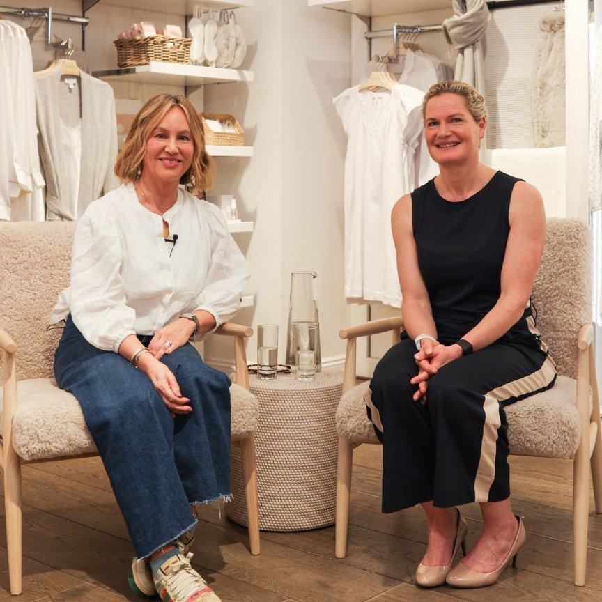 two women sitting in chairs in a store with clothes