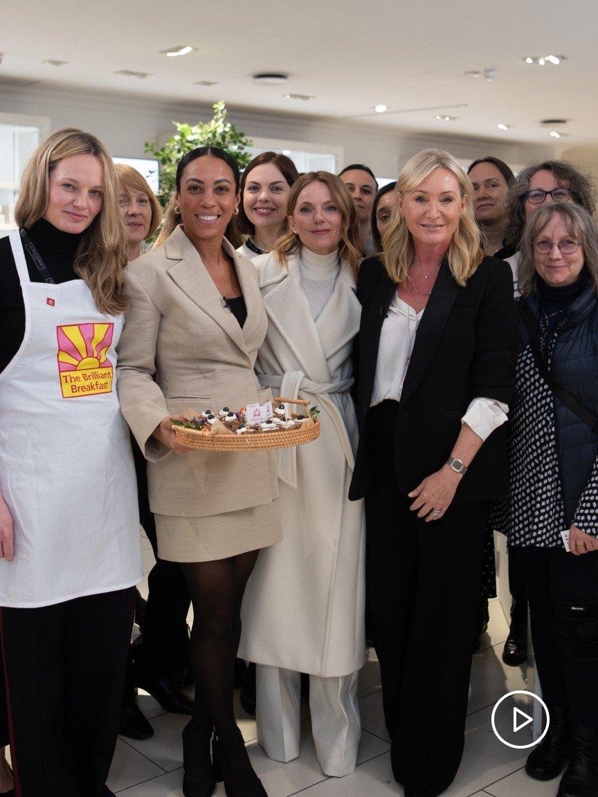a group of women standing together in a room with a cake