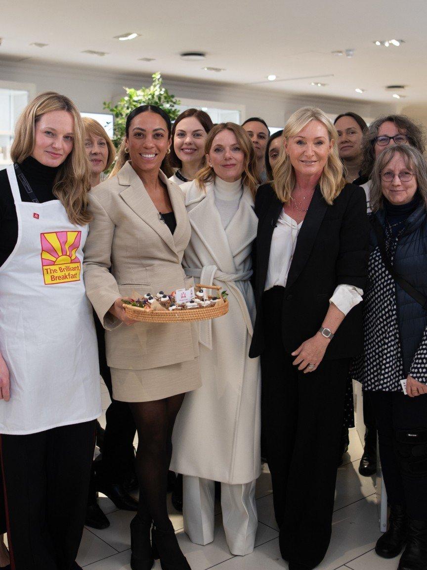 a group of women standing together in a room with a cake