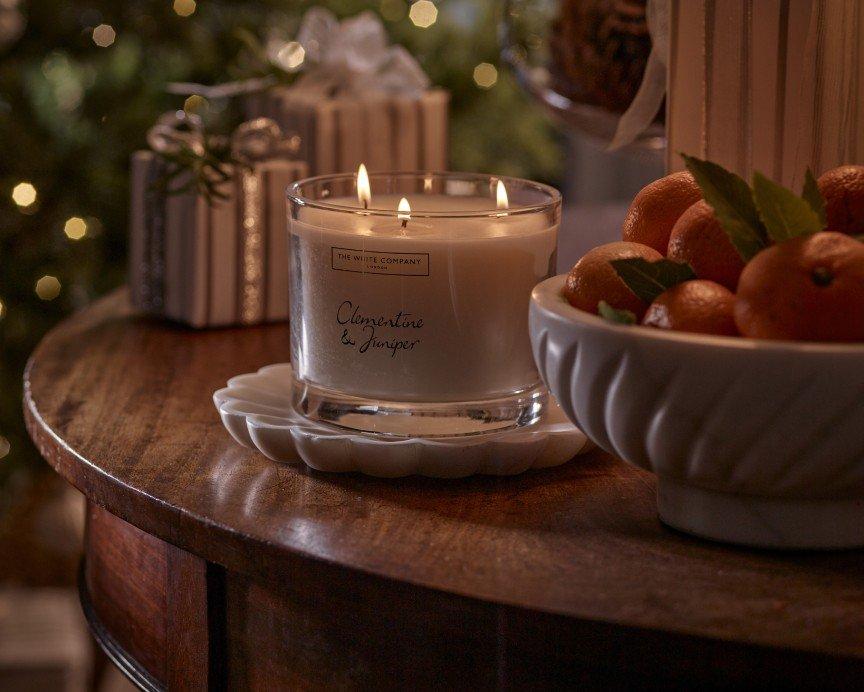 a candle is lit on a table next to a bowl of oranges