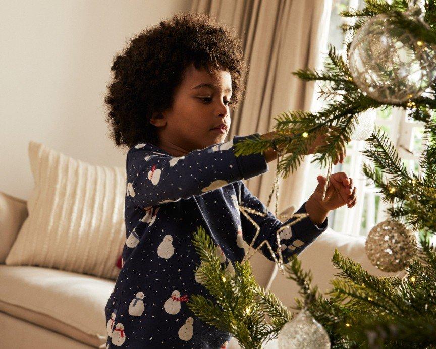 a young child decorating a christmas tree in a living room