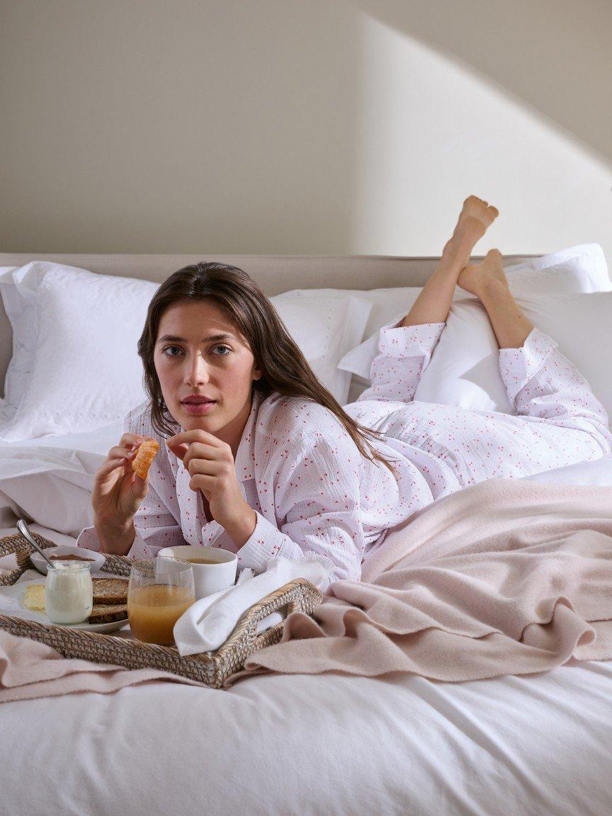 a woman laying in bed with breakfast and juice on tray