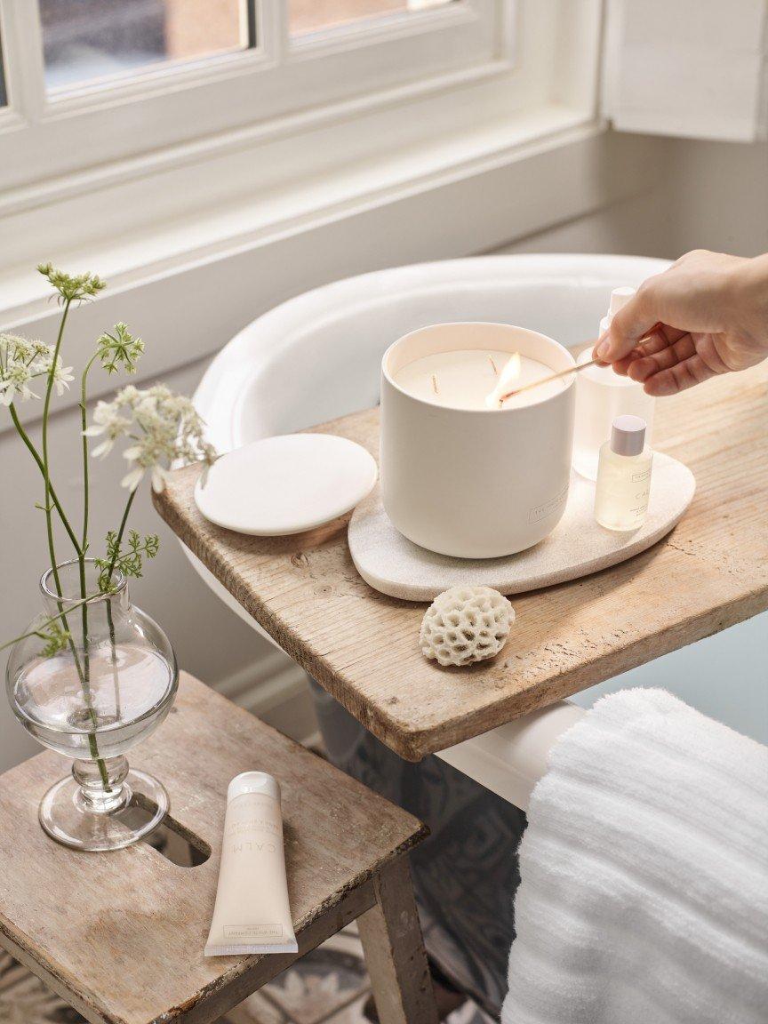 a person is holding a candle in a bathtub with flowers