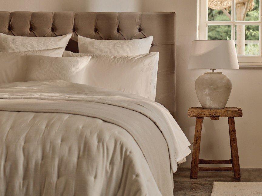 a bed with a white comforter and pillows in a bedroom