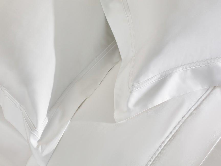 a close up of a bed with white sheets and pillows