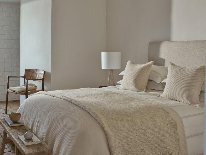 a bed with a white blanket and pillows in a bedroom