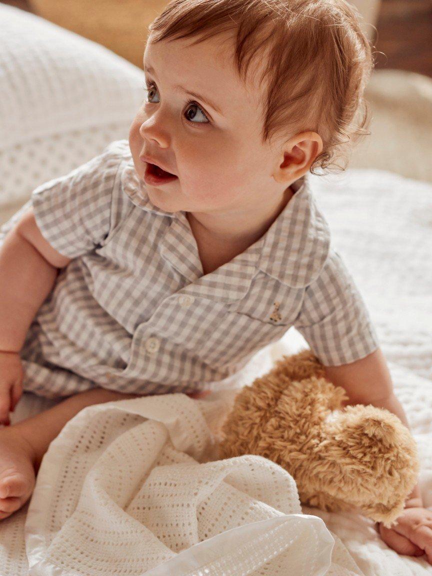 a baby boy laying on a bed with a teddy bear