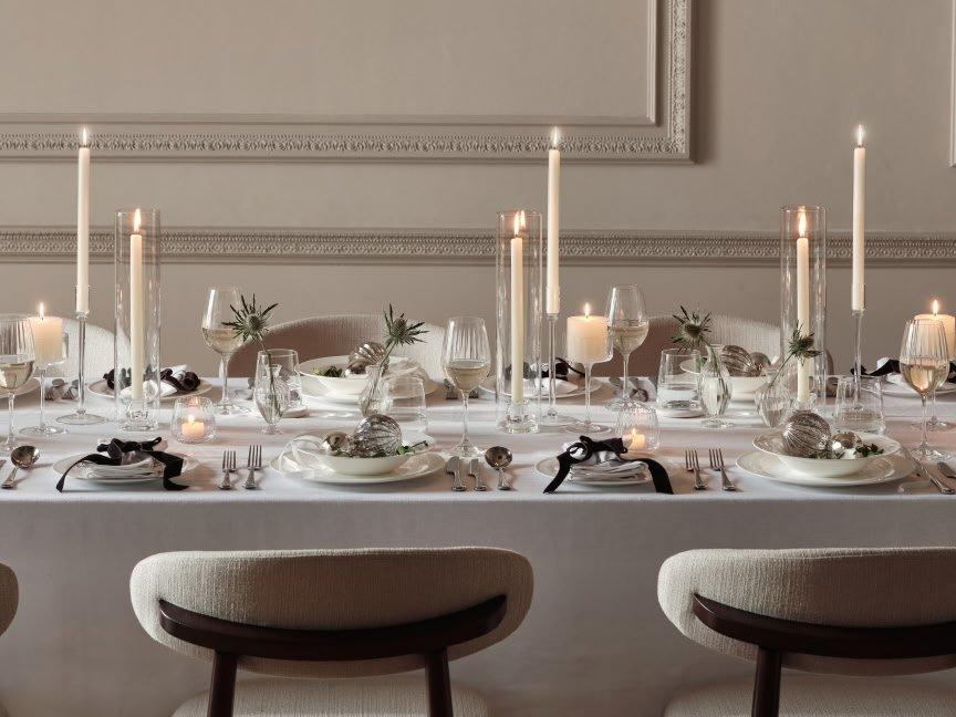 a table set for a formal dinner with candles and silverware