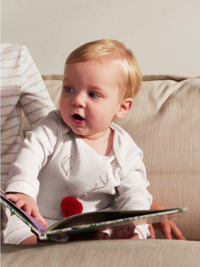 a baby sitting on a wooden floor wearing a white towel