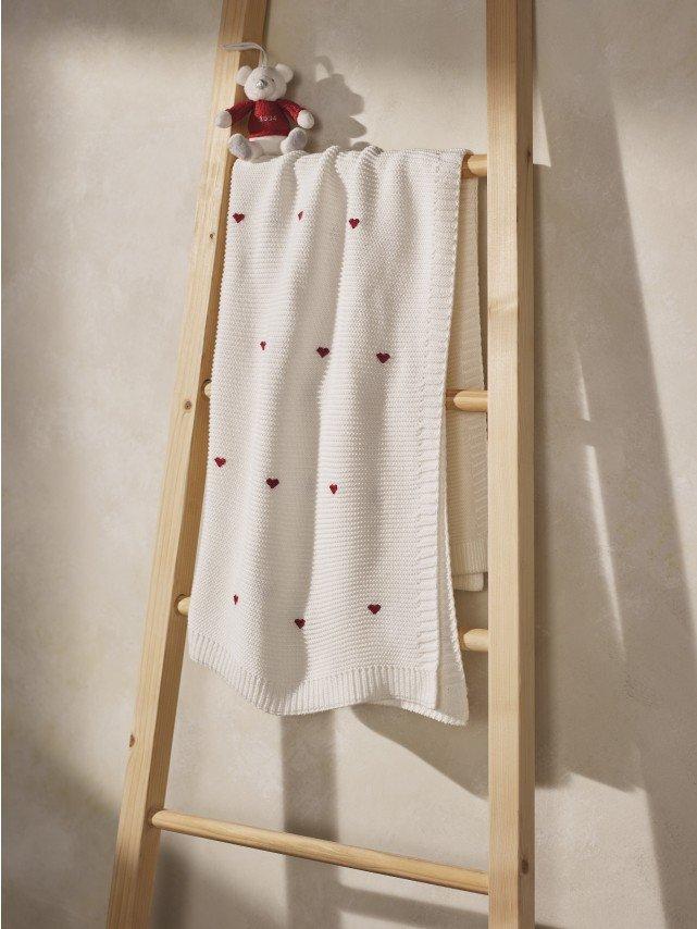 a baby is sitting on a bed wearing a white outfit