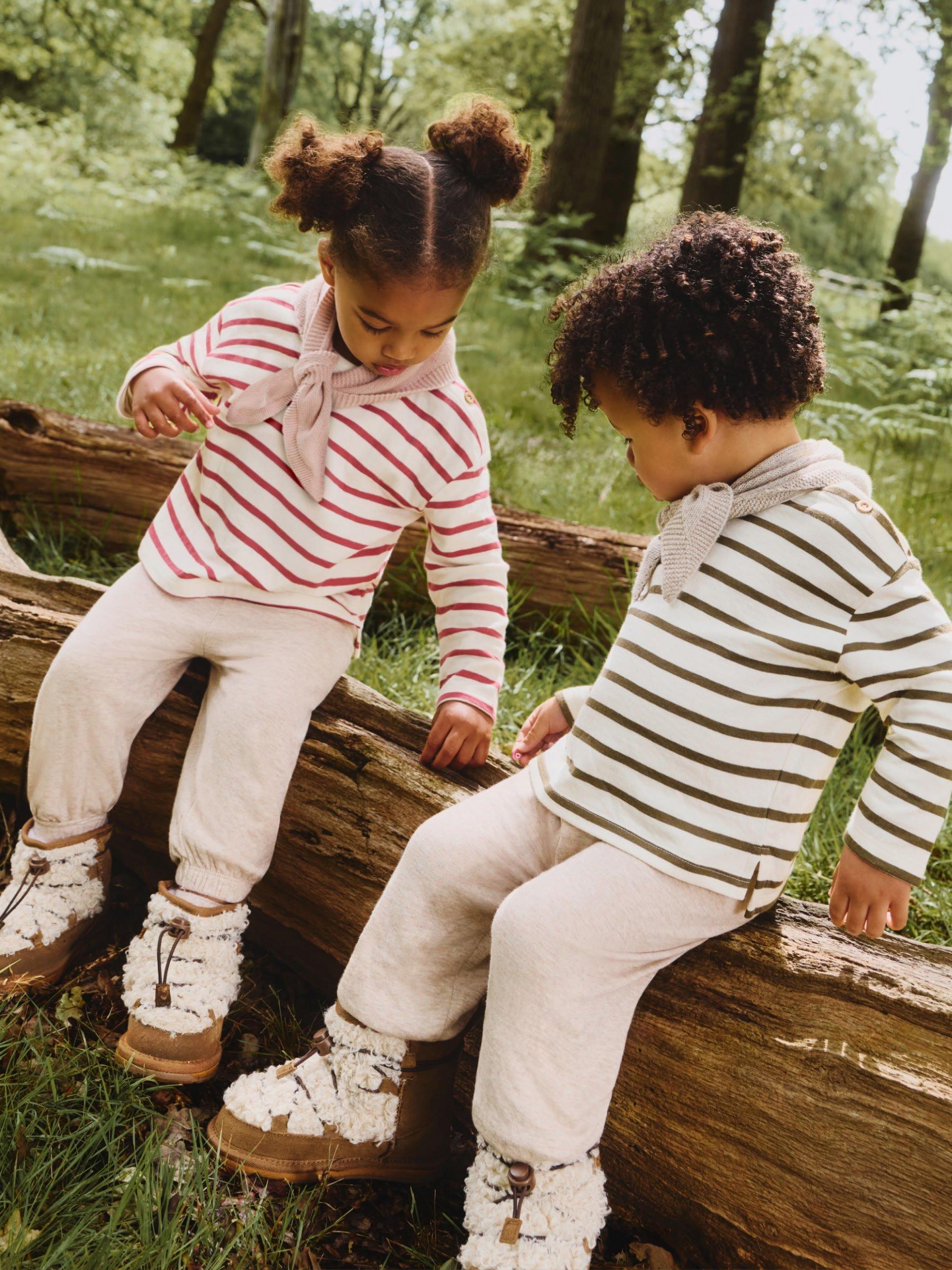 a boy and a girl in matching striped outfits in the woods