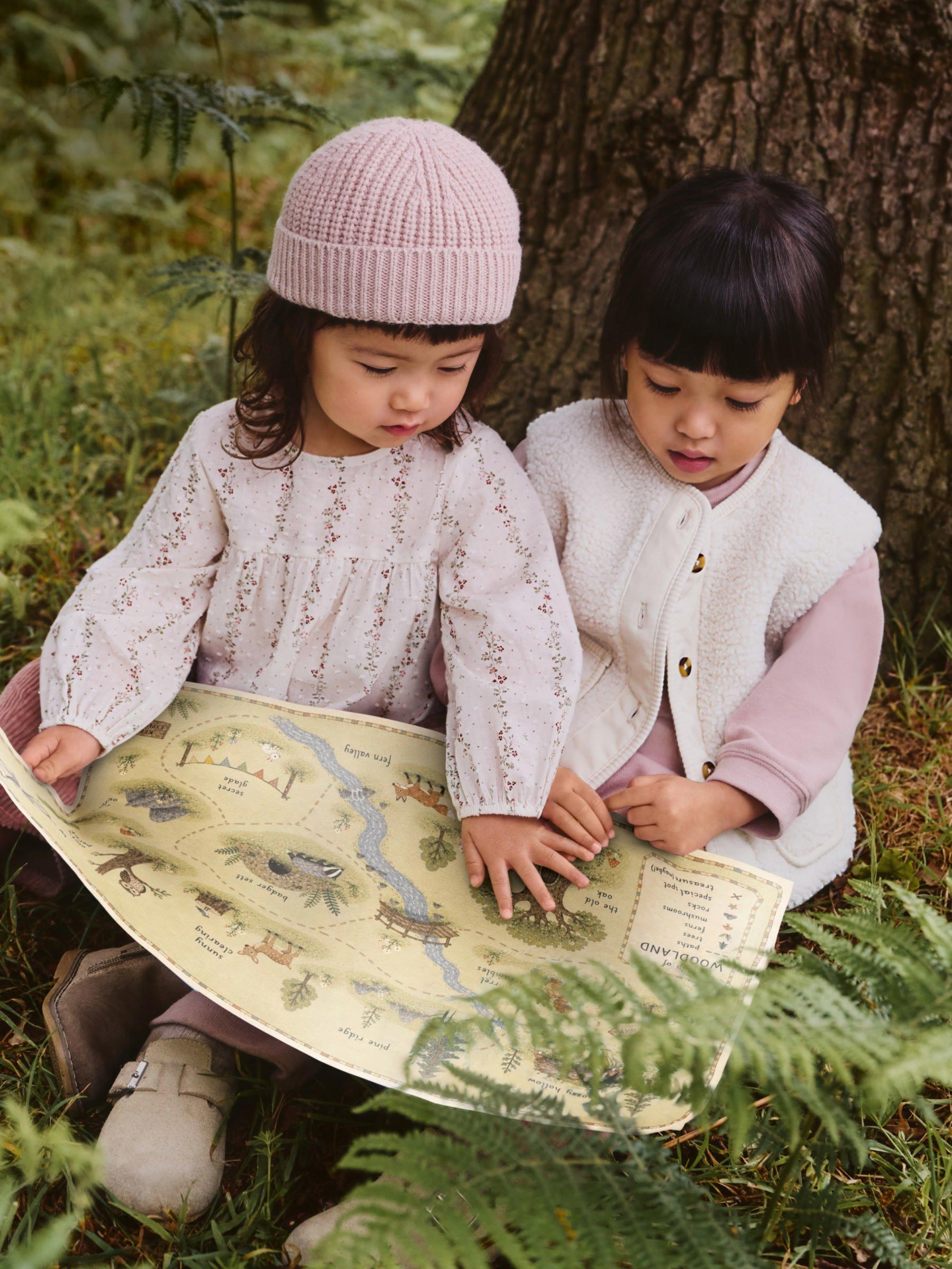 two girls dressed in pink reading a map