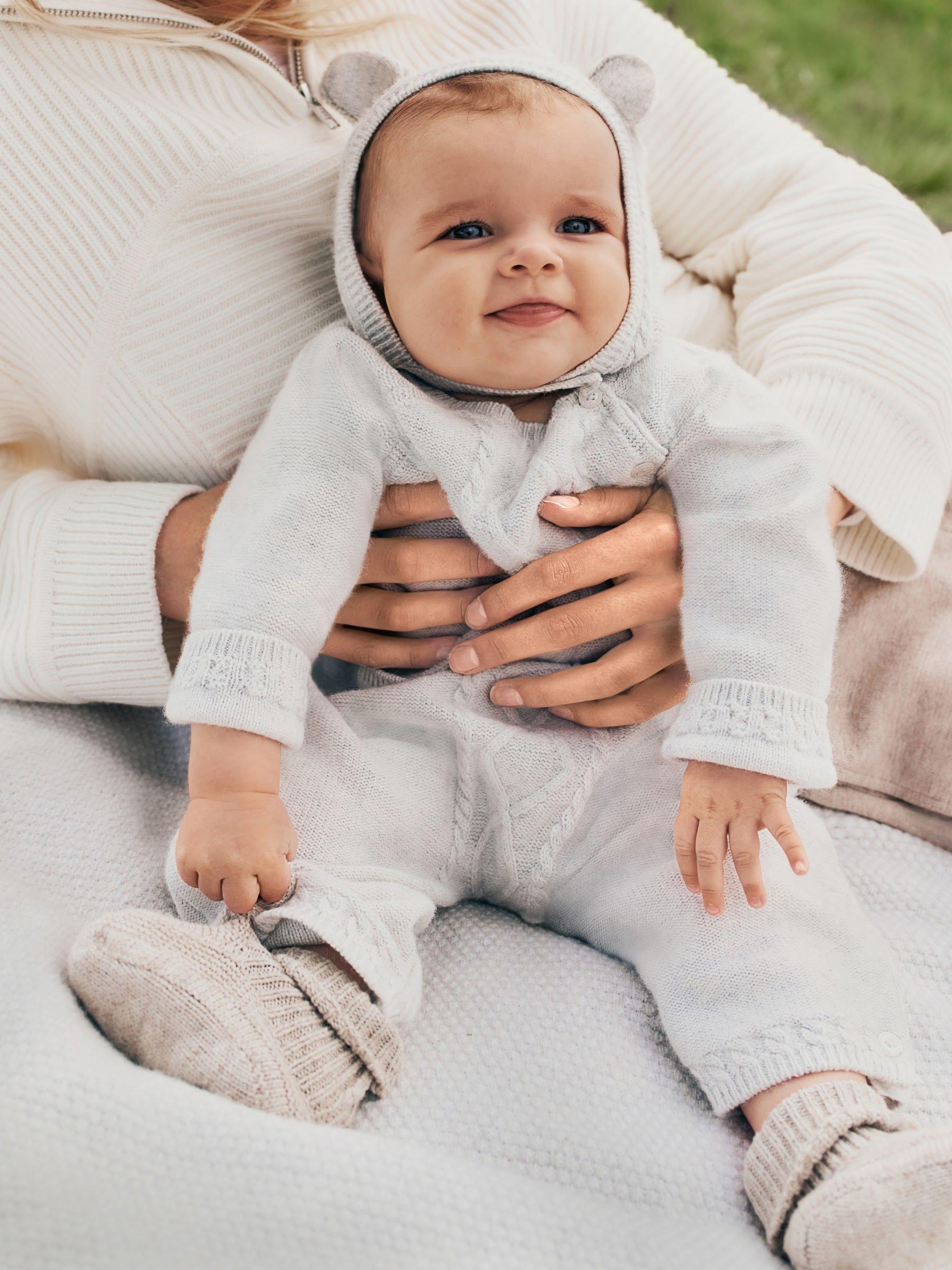 baby in knitted outfit being held