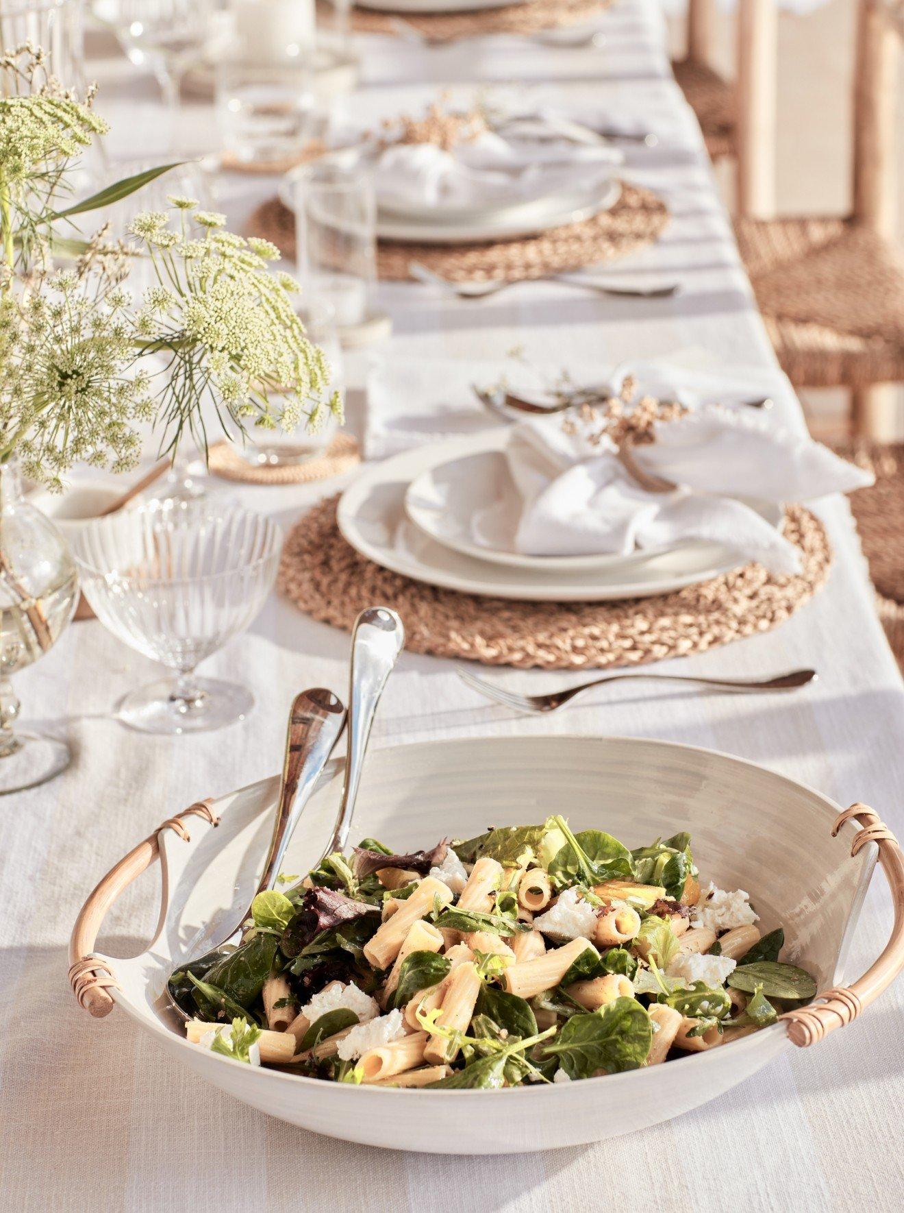 a table with a bowl of salad and silverware on it