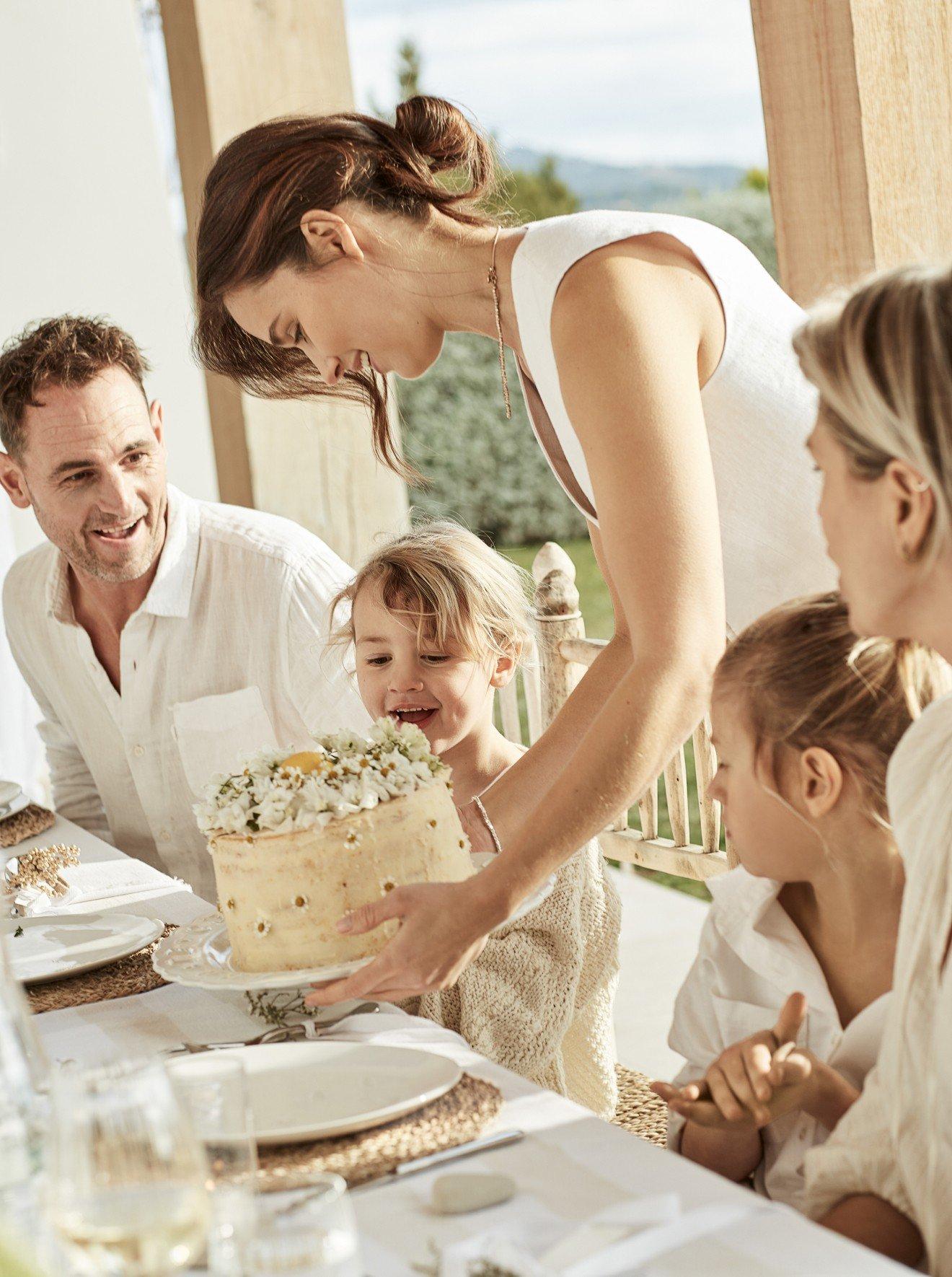 a woman and children sitting at a table with a cake