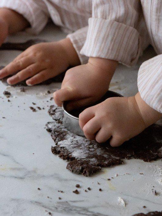 two children are making a chocolate cake on a table