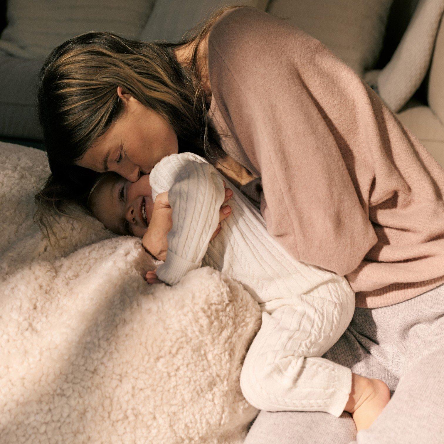 a woman cuddling a toddler on a bed