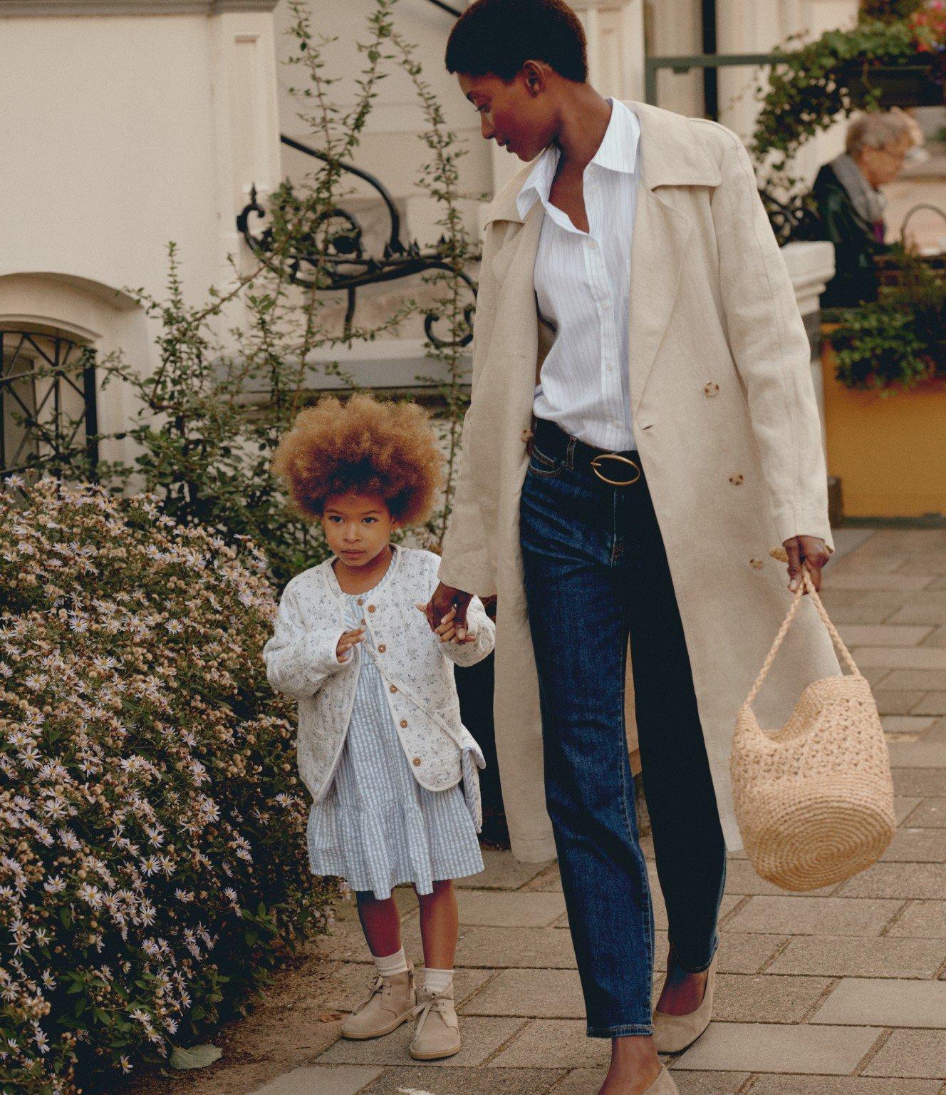 a woman and child walking down a sidewalk with a handbag