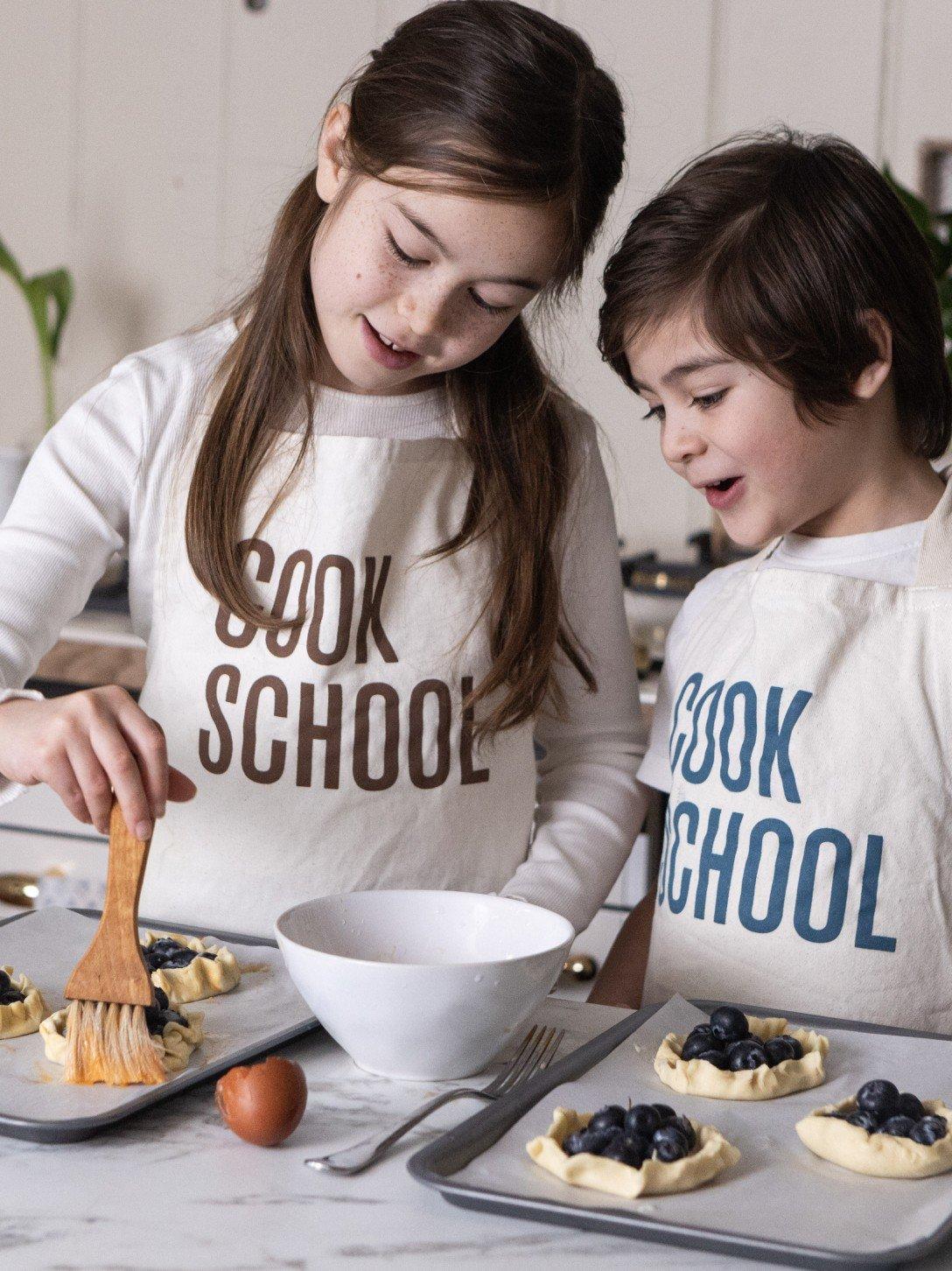 three young girls are preparing a meal in a kitchen