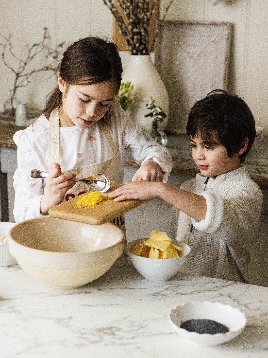 a boy and girl preparing food in a kitchen with a counter