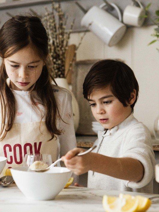 two children are preparing a meal in a kitchen