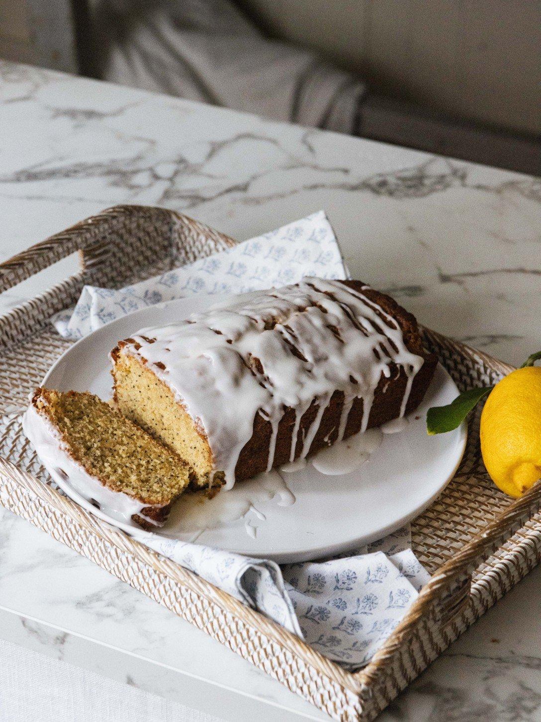 a loaf of cake with icing on a plate next to a lemon