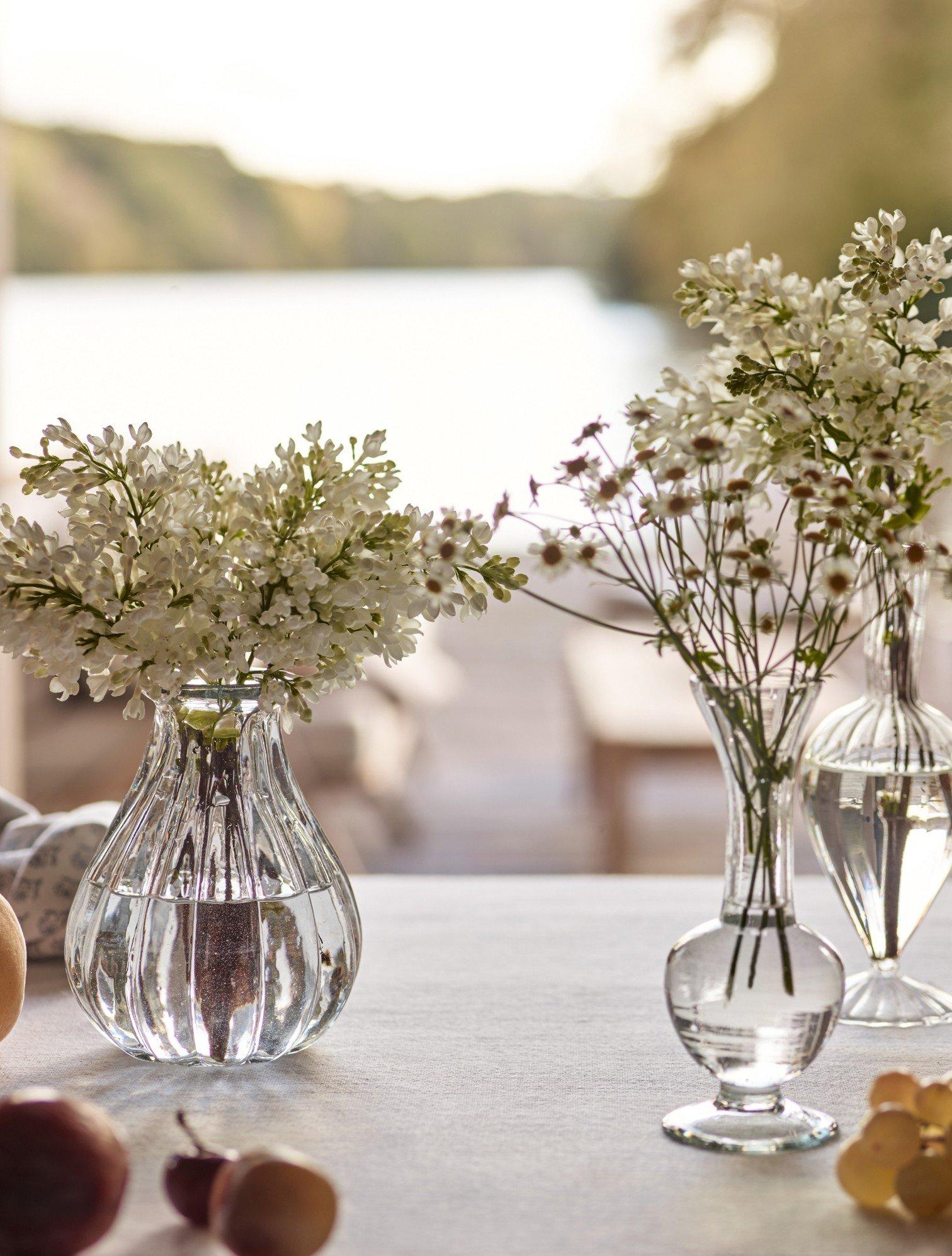 three vases of flowers on a table with a fruit bowl