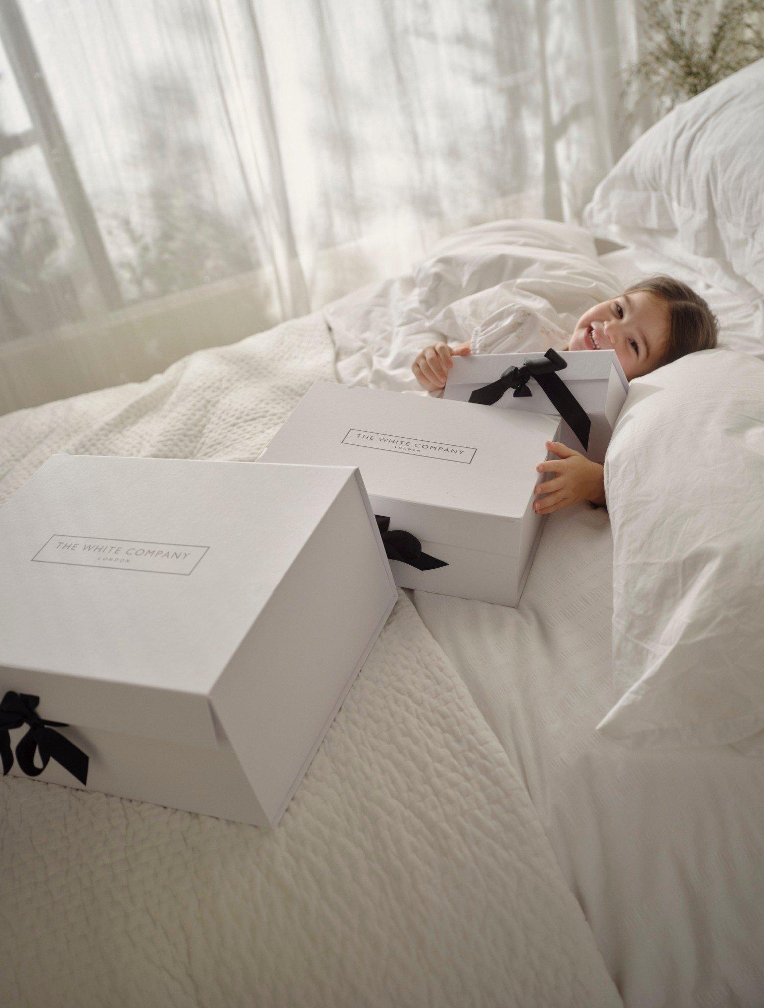 a little girl laying in bed with two boxes on either side of her