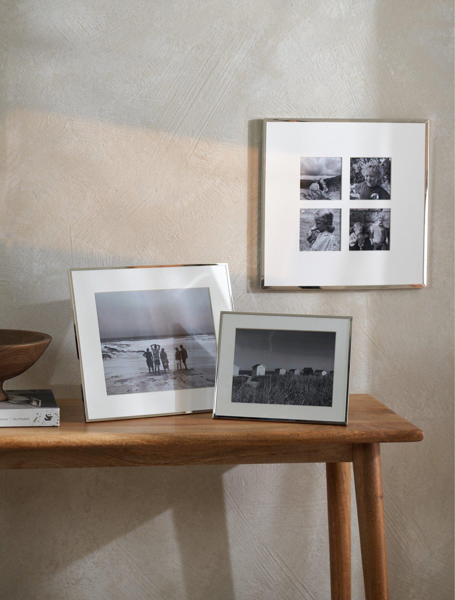a wooden table with three framed pictures on it and a bowl on it