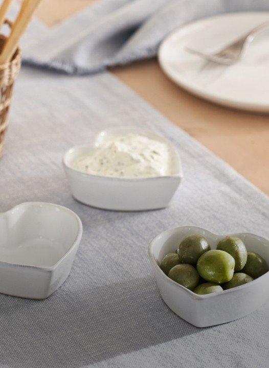 a table with three bowls of olives and a bowl of bread