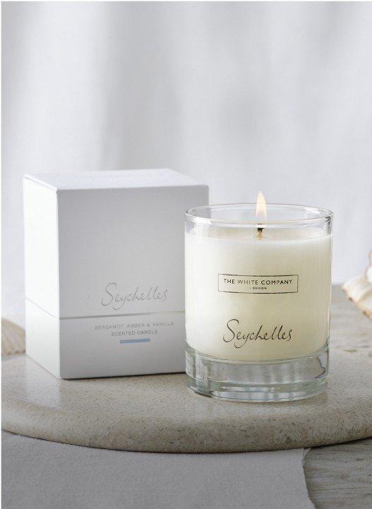 a candle sits on a marble slab next to a box of shells