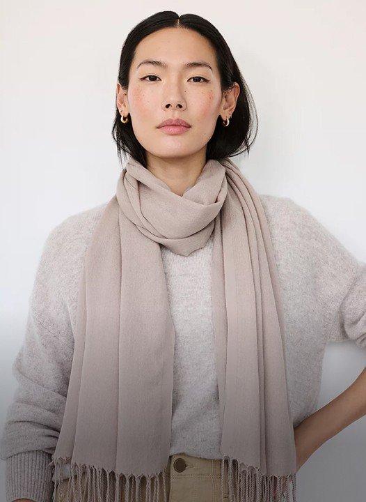 a woman wearing a grey scarf and a white shirt