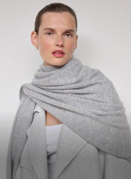 a woman wearing a grey scarf and a white shirt