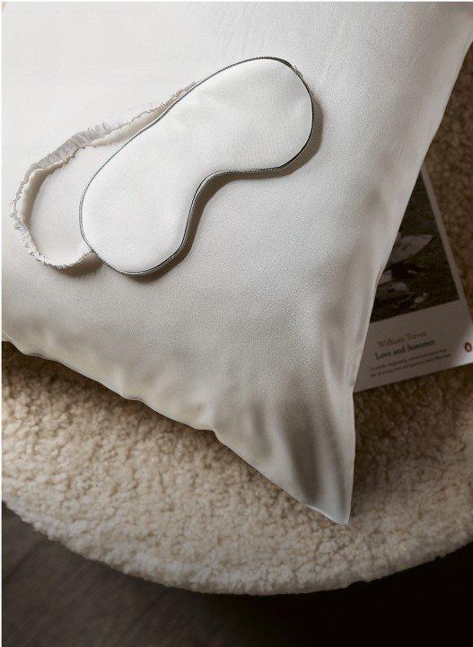 a white pillow with a white eye mask on it sitting on a bed