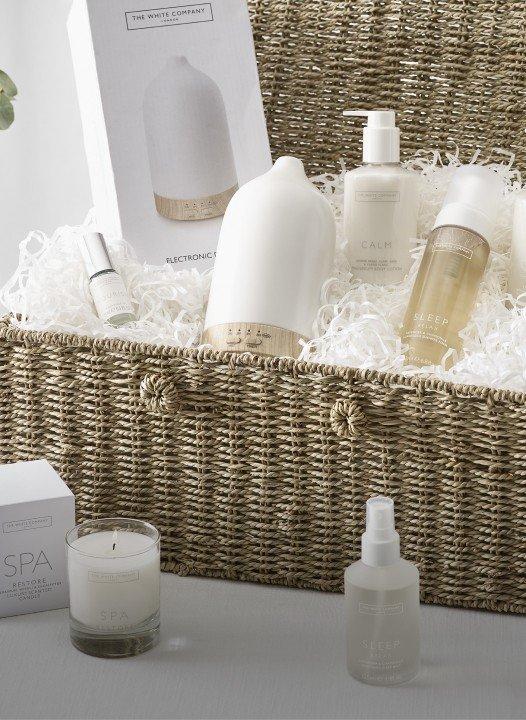 a wicker basket with a candle, lotion and other items