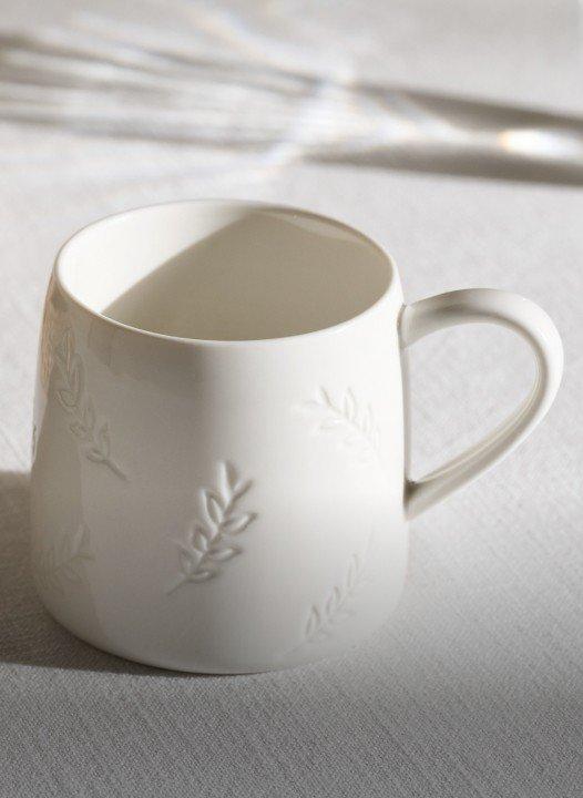 a white cup sitting on a table next to a bowl
