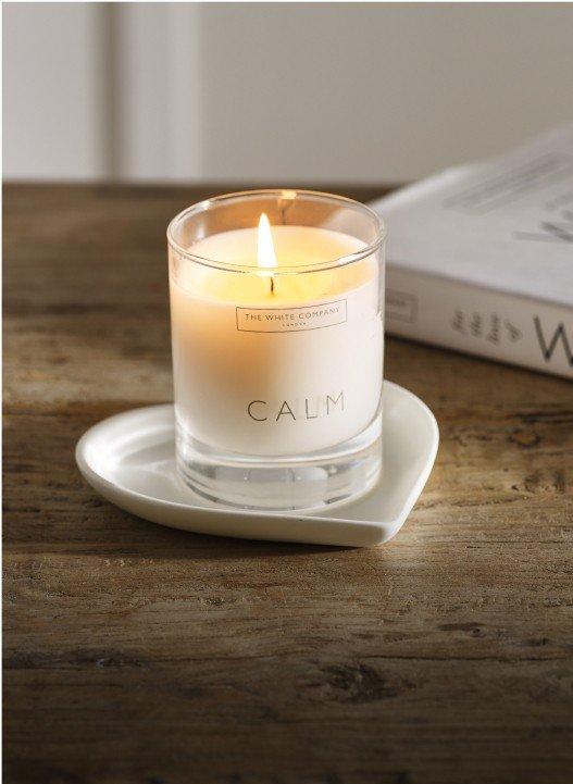 a candle sits on a wooden tray next to a book