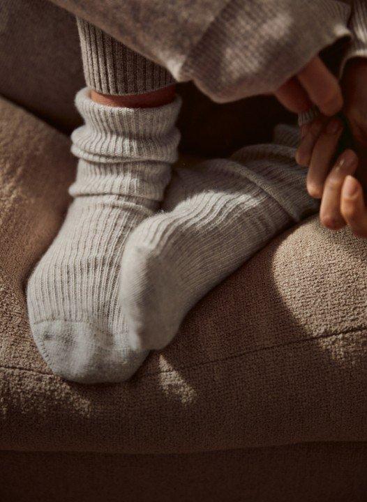 a person wearing a pair of grey socks on a couch