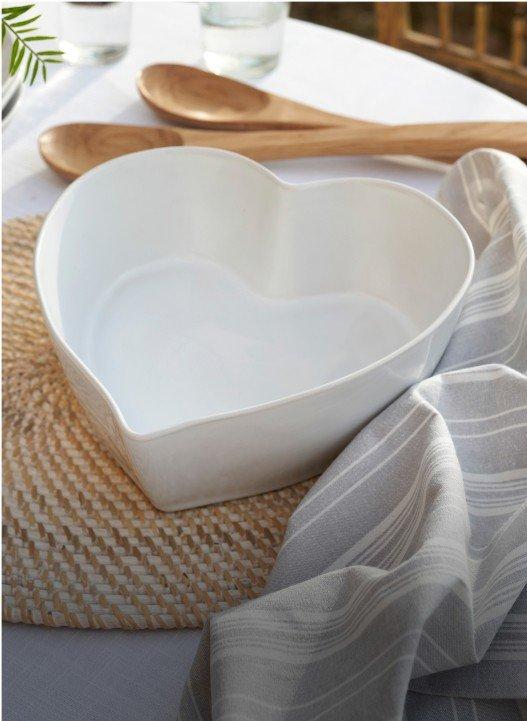 a white bowl sitting on a table with a wooden spoon