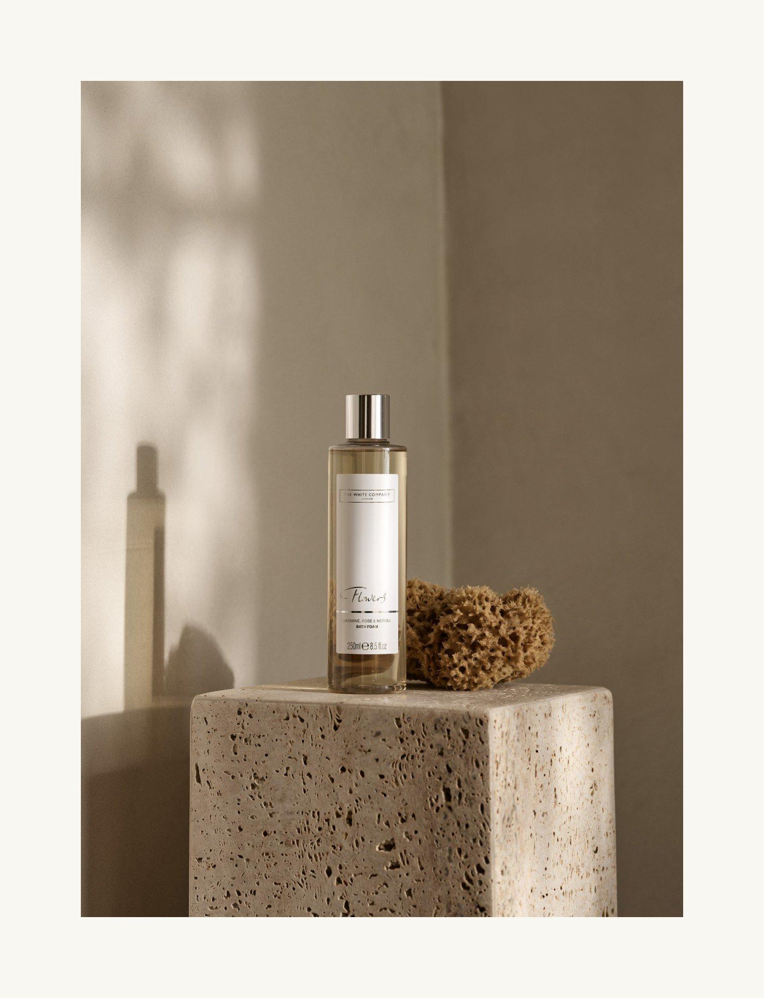 a bottle of perfume sitting on a block next to a rock