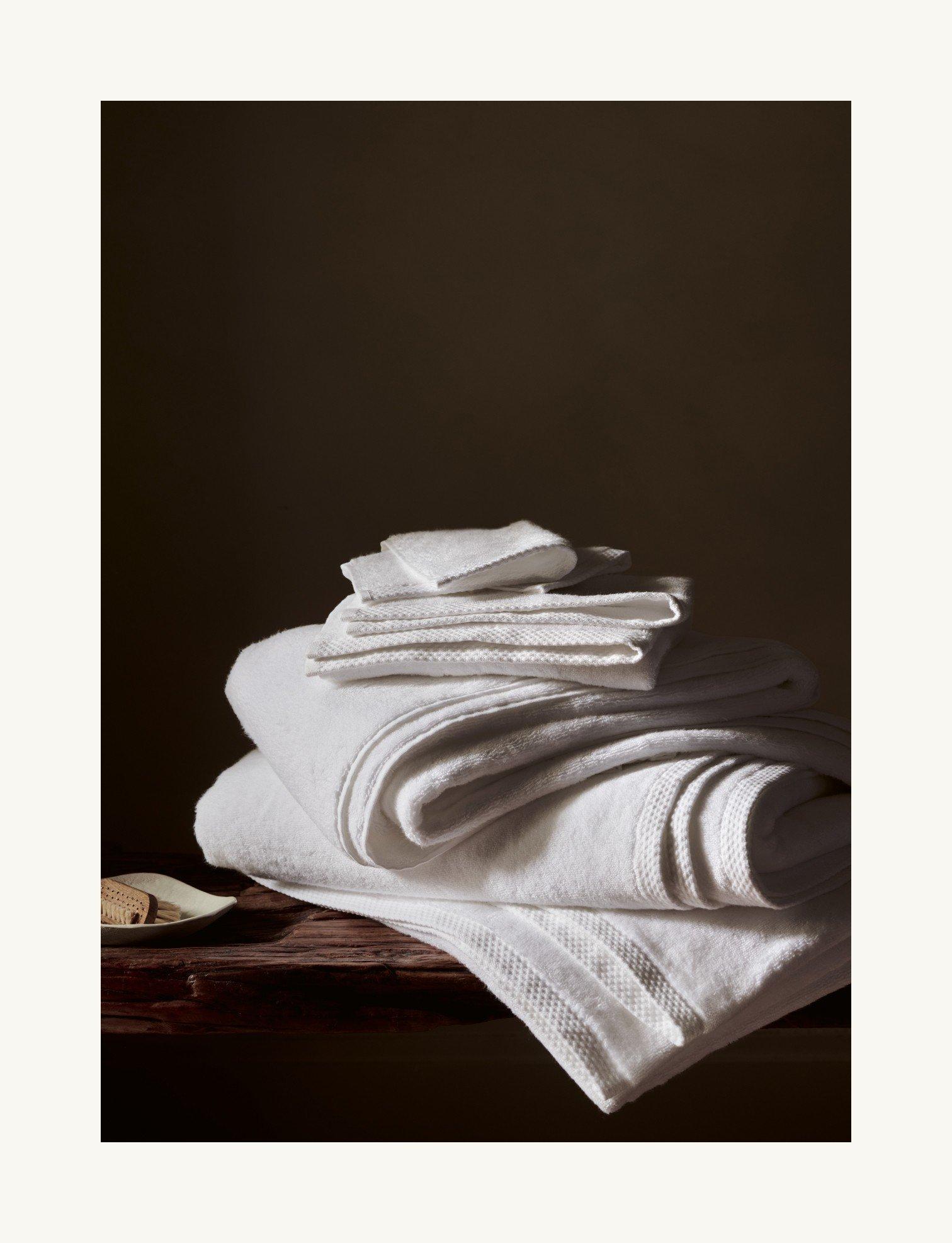 a stack of white towels on a wooden table with a wooden spoon