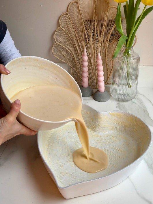 a person pouring a liquid into a heart shaped bowl